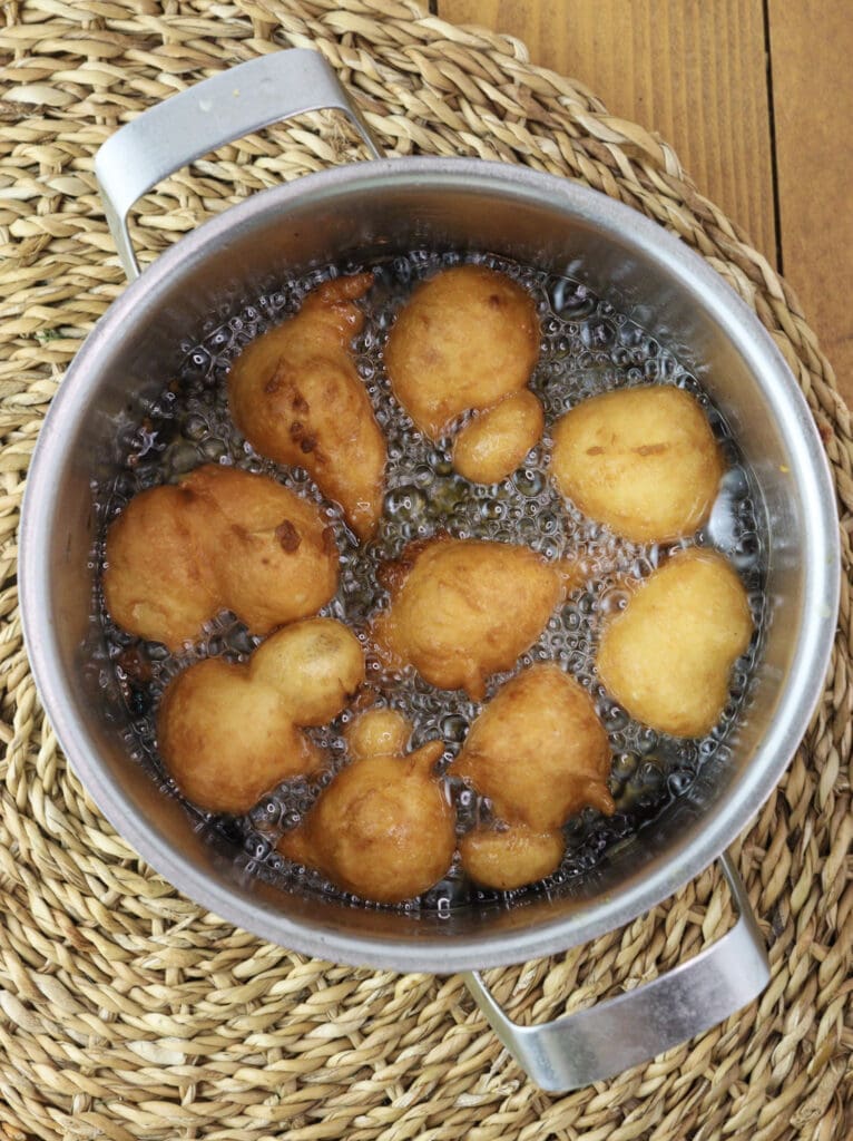 Fried dough balls in a pan with oil.